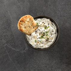 crackers and dip in a black bowl on a gray surface with green sprinkles