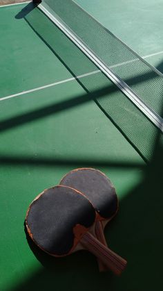 two ping pong paddles laying on top of a tennis court