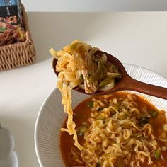 a wooden spoon full of noodles and vegetables