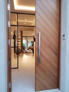 an open wooden door leading to a living room and dining area with white tile flooring