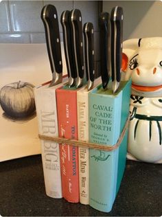 a stack of books sitting on top of a counter next to a knife holder with knives sticking out of it