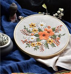 an embroidery kit with flowers and leaves on it, next to some other items in the background