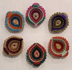 six colorful brooches are arranged on a white surface