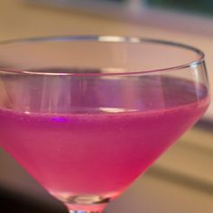 a pink drink in a wine glass on a table