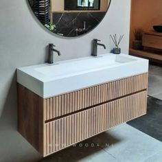 a bathroom sink with two faucets under a round mirror