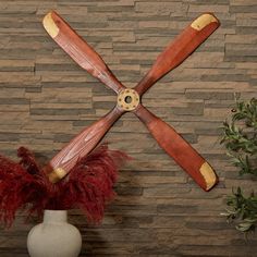 four wooden propellers mounted to the side of a wall next to a potted plant