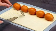 a person cutting eggs with a knife on top of a piece of parchmented paper