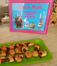 there is a green tray with pigs in a blanket on it next to a sign