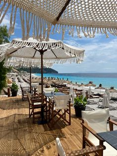 an outdoor dining area with tables and umbrellas on the beach, overlooking the ocean