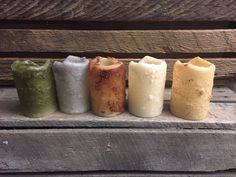 four different colored candles sitting on top of a wooden bench