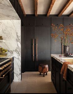 a kitchen with black cabinets and marble counter tops, along with a wooden stovetop