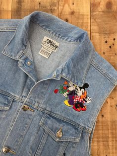 "Awesome 90's Mickey Mouse denim vest. Vest is in great & clean condition with little signs of previous wear. Perfectly worn in with naturally distressed denim character. Traditional Mickey Mouse embroidered emblems on front and back. Embroidery in great shape. Full button up front with adjustable buttons in back. Lightweight denim 100% cotton. See photos for details. Measurements (taken zipped-buttoned up and laid comfortably flat) x2 for total circumference (inches) Size Medium Shoulders 1 Retro Denim Vest For Fall, 90s Denim Vest For Fall, 90s Cotton Denim Vest With Pockets, 90s Style Cotton Denim Vest With Pockets, 90s Style Medium Wash Denim Vest For Spring, 90s Style Medium Wash Denim Vest, 90s Style Spring Denim Jacket, 90s Style Fitted Cotton Denim Vest, 90s Style Cotton Vest For Spring