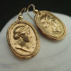 Handmade intaglio reproduction showing the ancient goddess Hera.Hera was a powerful goddess, the wife and sister of Zeus. She was worshiped as the Queen of Heaven as well as the Goddess of Marriage, Women and Birth. Roman equivalent Juno.- Handmade cameos- Solid yellow bronze also called jeweler gold bronze cameos. - 14k gold filled ear wire. - Gold filled has 100 times more gold than plated so does not rub or peel off. - Nickel free.- Reproduction of a 17th c. Victorian cameo.- Signed in the ba Elegant Hand Cast Gold Earrings, Brass Medallion Earrings For Pierced Ears, Elegant Hand Cast Drop Earrings, Elegant Hand Cast Brass Earrings, Handmade Yellow Gold Plug Earrings, Brass Medallion Earrings As A Gift, Handmade Symbolic Yellow Gold Earrings, Symbolic Round Earrings, Elegant Medallion Earrings For Gift