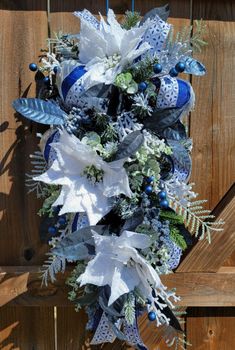 a blue and white christmas wreath hanging on a wooden fence