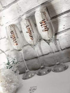 four wine glasses sitting on top of a table next to a vase with white flowers