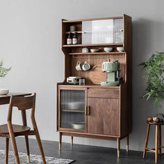 a wooden hutch with glass doors on the front and side, next to two chairs