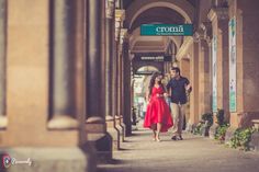 a man and woman walking down the sidewalk in front of an old building with a sign that says croma on it