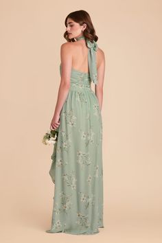 a woman in a long green dress with flowers on the back and one shoulder tied