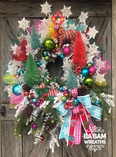 a christmas wreath is hanging on a door with ornaments around it and snowflakes