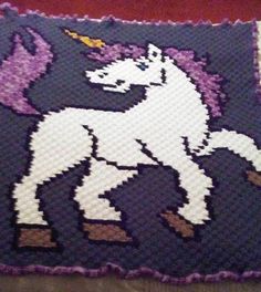 a close up of a knitted pillow with a unicorn on it's back