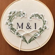 a white embroidered heart with flowers and the word m & i on it