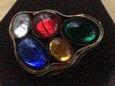 "Featuring this bold and stylish multi-colored glass stone three dimensional brooch. It has a gold tone setting and measures 1-3/4\" x 2-1/2\" and is 3/4\" thick. The brooch is in very good vintage condition with minor wear on the gold." Collectible Multicolor Costume Jewelry Brooches, Multicolor Cabochon Brooches For Collectors, Unique Multicolor Cabochon Brooches, Vintage Multicolor Round Brooches, Vintage Gold Brooch With Cabochon, Unique Multicolor Multi-stone Brooches, Vintage Multi-stone Yellow Gold Brooches, Vintage Multicolor Multi-stone Brooch, Nespresso Cups