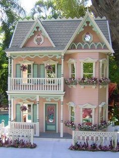 a pink doll house with flowers on the balcony