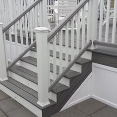 a set of stairs leading up to a deck with white railing and wood handrails