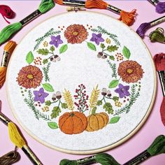 an embroidered hoop with flowers and pumpkins on it, surrounded by tassels