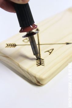 a person using a pen to draw an arrow on a piece of wood