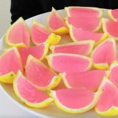 pink and yellow pieces of fruit on a white plate with someone holding it in the background