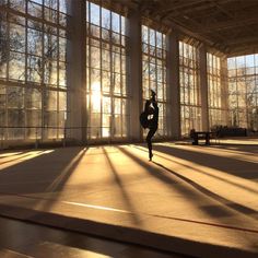 a person standing in front of large windows with the sun shining through them and their shadow on the floor