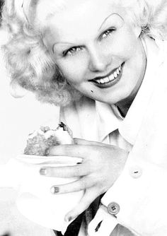 black and white photograph of a woman with blonde hair holding a piece of cake in her hands