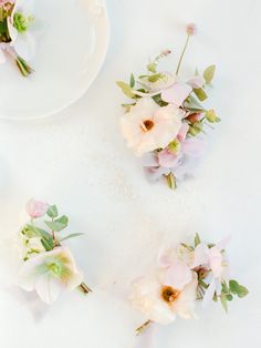 three white plates with pink flowers and greenery on them, sitting next to each other