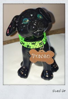 a black dog figurine with a bone tag on it's collar, sitting on a table