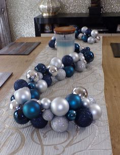 the table is decorated with blue and silver christmas balls, ornaments, and a candle