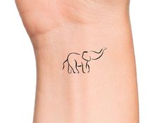 an elephant tattoo on the wrist is shown in black ink and has a small outline