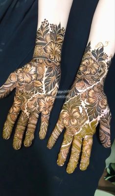 two hands with henna tattoos on them, one is gold and the other is brown