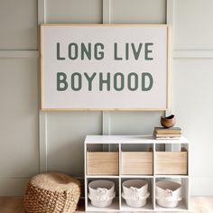 a sign that says long live boyhood next to some baskets and a hat on the floor