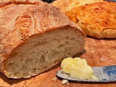 a loaf of bread sitting on top of a wooden cutting board next to a knife