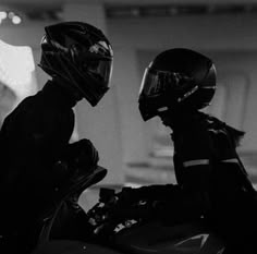 two people wearing helmets sitting on a motorcycle