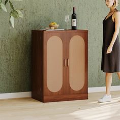 a woman standing next to a cabinet with a bottle of wine on top of it