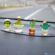 three small glass cactus plants sitting on top of a black table next to each other