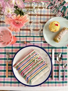 a table topped with plates and cups filled with cake next to utensils on top of a checkered table cloth