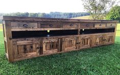 a large wooden cabinet sitting on top of a lush green field