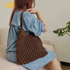 a woman sitting on top of a couch holding a brown crocheted bag with handles