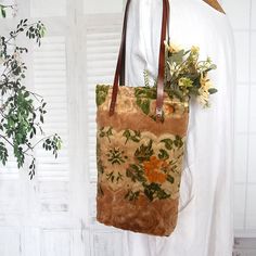 a brown bag with flowers on it sitting next to a white wall and window sill