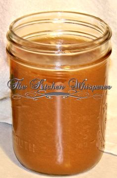 a glass jar filled with brown liquid sitting on top of a white cloth covered table