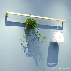 a white purse hanging on a blue wall next to a plant