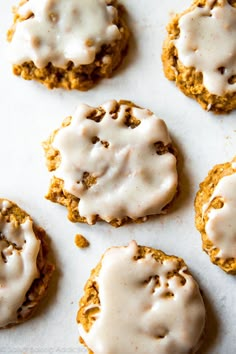 six cookies with white icing on a baking sheet